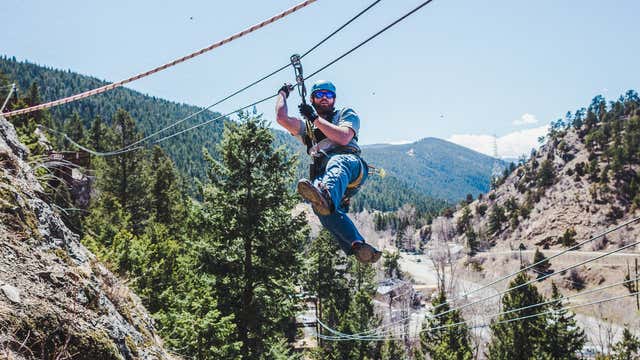 A person in the middle of a zipline with mountains in the background